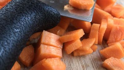 Karotten, Möhren bereits fein geschnitten, mit einem groben Messer auf einem Holzbrett
