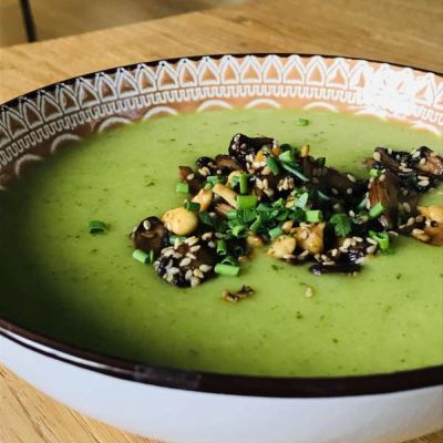 grüne Brokkolisuppe mit gebratenen Pilzen, Cashews und Sesam angerichtet in einer hübschen Suppentasse